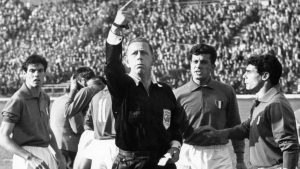 Tumultartige Szenen am 2. Juni 1962 vor 66.000 Zuschauern im Nationalstadion in Santiago de Chile im Fuall-WM-Gruppenspiel zwischen Italien und Chile. Wieder liegt ein Spieler verletzt am Boden, und eine Spielertraube um ihn herum diskutiert. Der englische Schiedsrichter Ken Aston (m.),.der das Spiel nicht unter Kontrolle bekommt, winkt Betreuer auf das Spielfeld, und die italienischen Akteure Salvadore (l.), Tumburus (2.v.r.) und Mora (r.) reden auf ihn ein. Die Begegnung entwickelt sich wegen vieler Taetlichkeiten und Fouls zum Skandalspiel. Zwei Italiener werden des Feldes verwiesen. Chile gewinnt am Ende gegen die reduzierte Azzurri-Elf mit 2:0. (KEYSTONE/EPA/STR) === BLACK AND WHITE ===