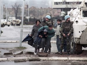 The residents of Sarajevo take cover from sniper fire behind a United Nations Protection Force (UNPROFOR) armoured vehicle in this 1993 file photo. Genocide, siege and massacre are for many people in Bosnia more than just words on Radovan Karadzic's indictment. They represent years of suffering, dead friends and nightmares that will always haunt them. To match feature WARCRIMES-KARADZIC/LEGACY REUTERS/Danilo Krstanovic/Files (BOSNIA AND HERZEGOVINA) - GM1E47U1NUO01