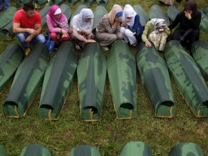 Bosnian woman cry beside coffins of relatives, which are amongst the 409 coffins of newly identified victims of the 1995 Srebrenica massacre, in Potocari Memorial Center, near Srebrenica July 11, 2013. The bodies of the recently identified victims will be transported to the memorial centre in Potocari where they will be buried on July 11 marking the 18th anniversary of the massacre in which Bosnian Serb forces commanded by Ratko Mladic killed up to 8,000 Muslim men and boys and buried them in mass graves. REUTERS/Dado Ruvic (BOSNIA AND HERZEGOVINA - Tags: SOCIETY CIVIL UNREST) - GM1E97B1DOK01