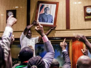 TOPSHOT - People remove, from the wall at the International Conference centre, where parliament had their sitting, the portrait of former Zimbabwean President Robert Mugabe after his resignation on November 21, 2017 in Harare. Robert Mugabe resigned as president of Zimbabwe on November 21, 2017 swept from power as his 37-year reign of brutality and autocratic control crumbled within days of a military takeover. The bombshell news was delivered by the parliament speaker to a special joint session of the assembly which had convened to impeach Mugabe, 93, who has dominated every aspect of Zimbabwean public life since independence in 1980.  / AFP PHOTO / Jekesai NJIKIZANA        (Photo credit should read JEKESAI NJIKIZANA/AFP/Getty Images)