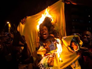 A Zimbabwean national burns a shirt of the Zimbabwe's ruling party, the Zimbabwe African National Union Patriotic Front (ZANU PF), as hundreds of Zimbabweans living in South Africa celebrate the resignation of Zimbabwe's president Robert Mugabe in the streets of the district of Hillbrow in Johannesburg on November 21, 2017. The announcement came after days of mounting pressure on the 93-year-old leader, whose long and authoritarian rule made him feared by many of his citizens. / AFP PHOTO / WIKUS DE WET        (Photo credit should read WIKUS DE WET/AFP/Getty Images)