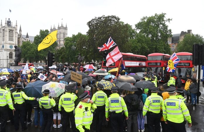 Протестиращи срещу локдауна държат плакати, докато се събират в Уестминстър в Лондон, Великобритания, 21 юни 2021 г.