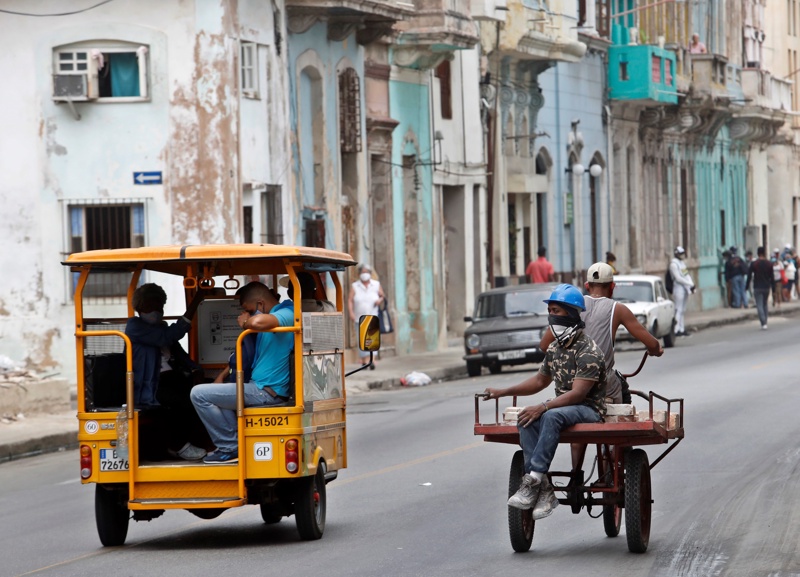 Хора карат триколки по улица в Хавана, Куба