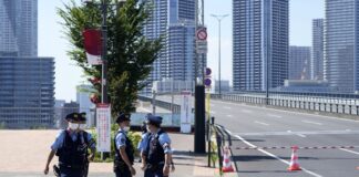 Полицейски служители пред Олимпийското село (вижда се на заден план) в Токио, Япония, 17 юли 2021г.