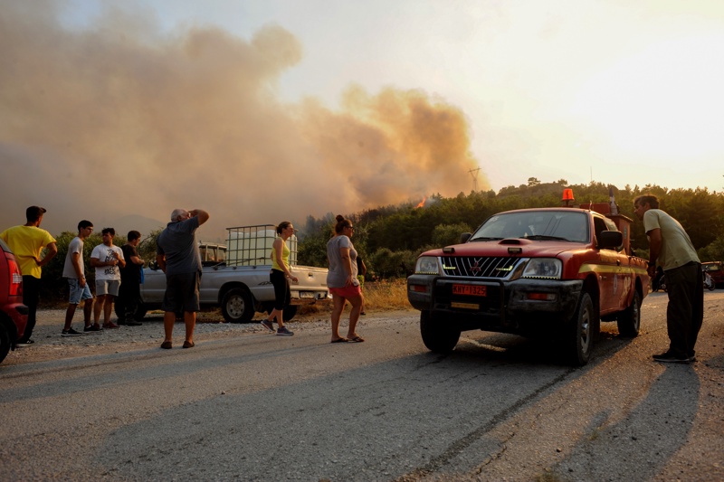 Туристи и жители наблюдават горския пожар в района на Каламонас, остров Родос, Гърция, 01 август 2021г. 