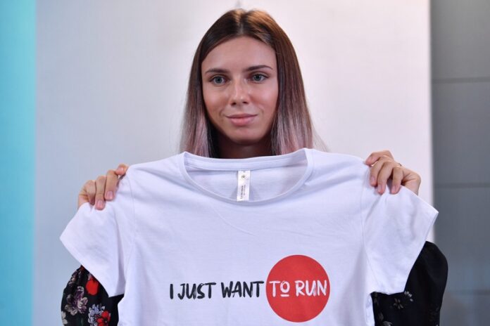 Кристина Tимановская показва тениска с надпис „Просто искам да бягам“, по време на пресконференция във Варшава, Полша, 05 август 2021г.
