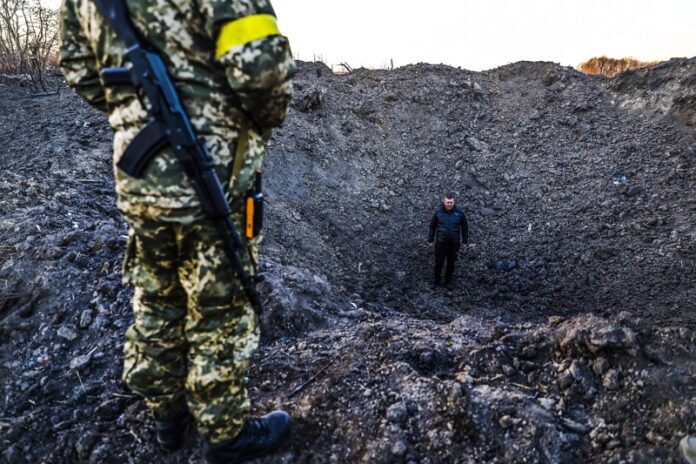Мъж стои в кратер от бомба близо до бензиностанция, отоплителна станция и главната топлопроводна мрежа, които бяха разрушени след бомбардировките в Житомир, Украйна