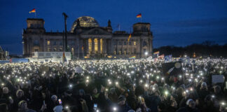 Демонстранти са включили фенерчетата на мобилните си телефони в знак на протест срещу крайната десница в Германия пред сградата на Райхстага в столицата Берлин, 21 януари 2024 г.