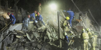 Украински спасители търсят оцелели сред развалините на разрушена сграда при днешната руска ракетна атака срещу Киев.