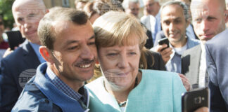 На тази снимка от 9 септември 2015 г. германската канцлерка Ангела Меркел позира за селфи с бежанец в център за пристигащи бежанци в Берлин.