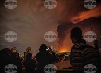 Жители наблюдават пламъци и дим, които се издигат от склад за петрол, поразен при удари срещу Техеран, 7 март 2026 г.
