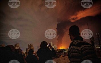 Жители наблюдават пламъци и дим, които се издигат от склад за петрол, поразен при удари срещу Техеран, 7 март 2026 г.