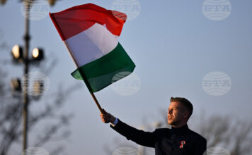 идерът на унгарската опозиция Петер Мадяр развява знамето на Унгария по време на предизборно събитие в Будапеща, 15 март 2026 година.