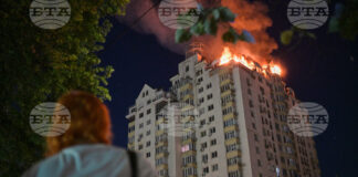 Жена наблюдава горящ жилищен блок по време на нощната руска атака срещу Киев, 2 юли 2026 г.
