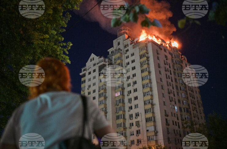Жена наблюдава горящ жилищен блок по време на нощната руска атака срещу Киев, 2 юли 2026 г.