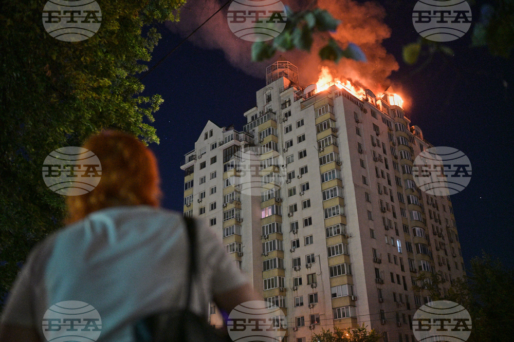 Жена наблюдава горящ жилищен блок по време на нощната руска атака срещу Киев, 2 юли 2026 г.