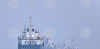 Малка моторна лодка преминава покрай кораби на котва в Ормузкия проток край Бандар Абас, 11 юни 2026 г.