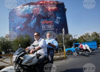 Иранци подминават на мотоциклет билборд в столицата Техеран, изобразяващ президента на САЩ Доналд Тръмп потънал сред експлозии с надпис "Голяма победа! Ормузкият проток", 24 август 2026 г.