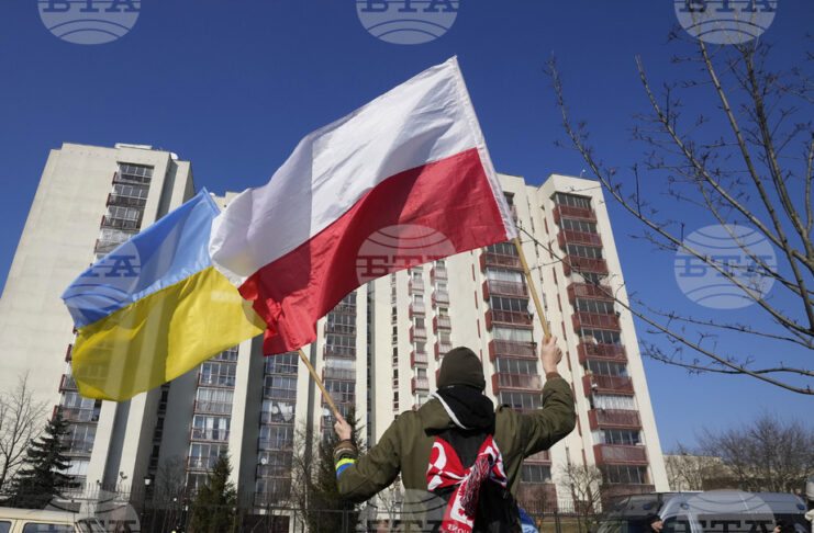 Мъж държи знамената на Полша и на Украйна по време на протестна проява пред руското посолство във Варшава.
