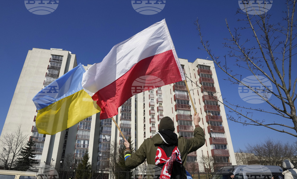 Мъж държи знамената на Полша и на Украйна по време на протестна проява пред руското посолство във Варшава.