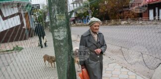 Възрастна жена върви под мрежи срещу дронове, опънати над улица по време на местно прекратяване на огъня, свързано с евакуационни дейности в Олешки, Херсонска област, Украйна на 27 октомври 2026 г.
